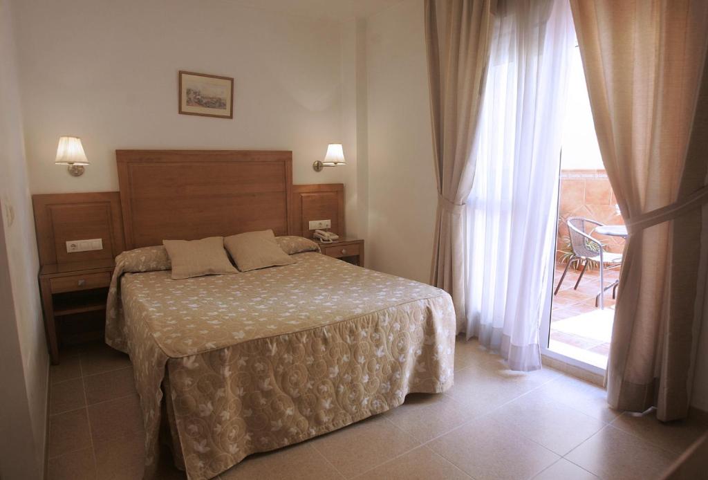 a bedroom with a bed and a large window at Hotel Goartín in Málaga