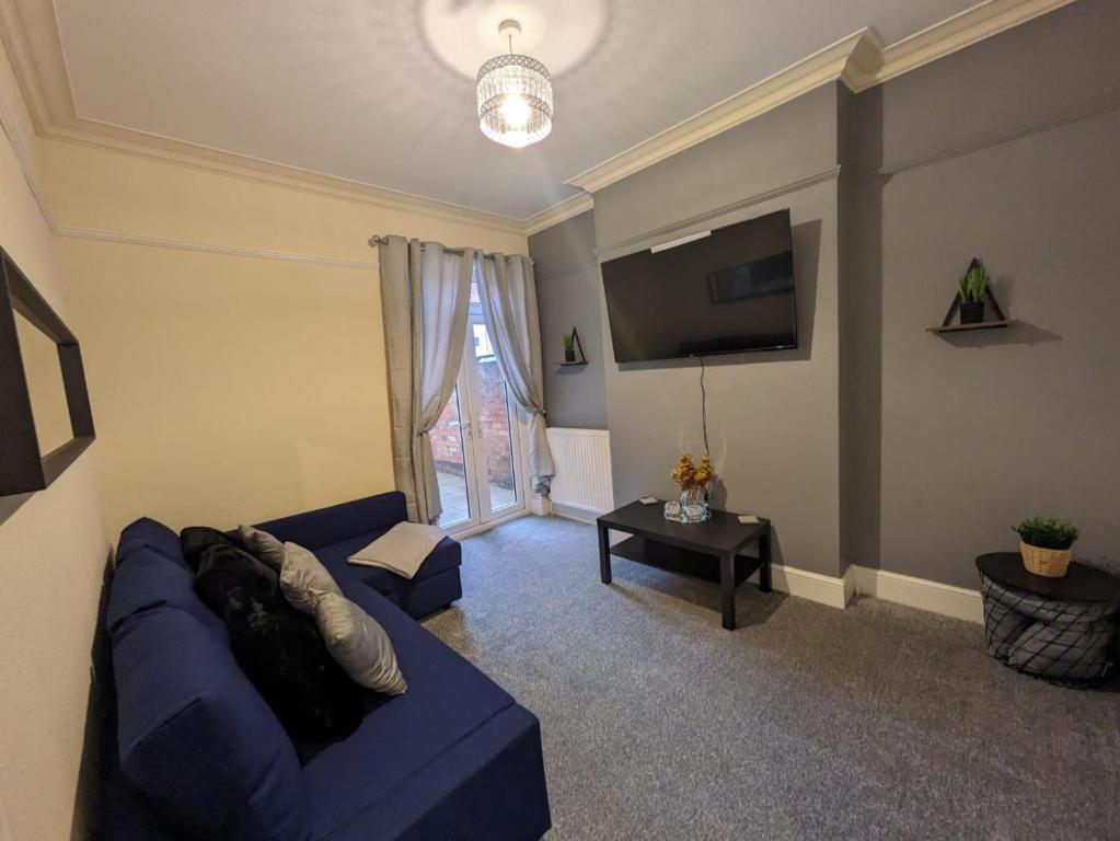 - un salon avec un canapé bleu et une fenêtre dans l'établissement Beacon House, à Leicester