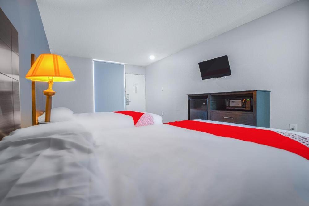 um quarto com 2 camas, um candeeiro e uma televisão em StateLine Stayovers Extended Stay Hotel em Texarkana