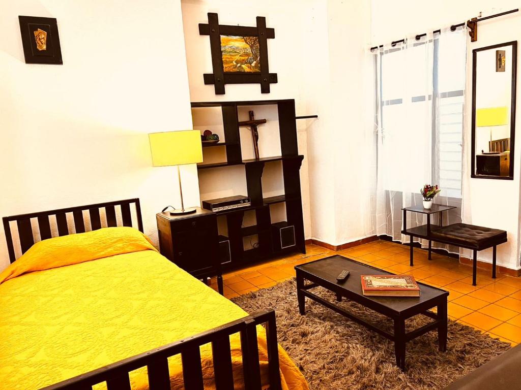a bedroom with a yellow bed and a table at Titos Centric Home in Morelia