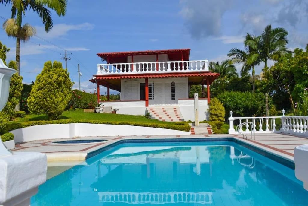 une maison avec une piscine en face d'une maison dans l'établissement Finca con billar y piscina para un Descanso Familiar, à Pereira