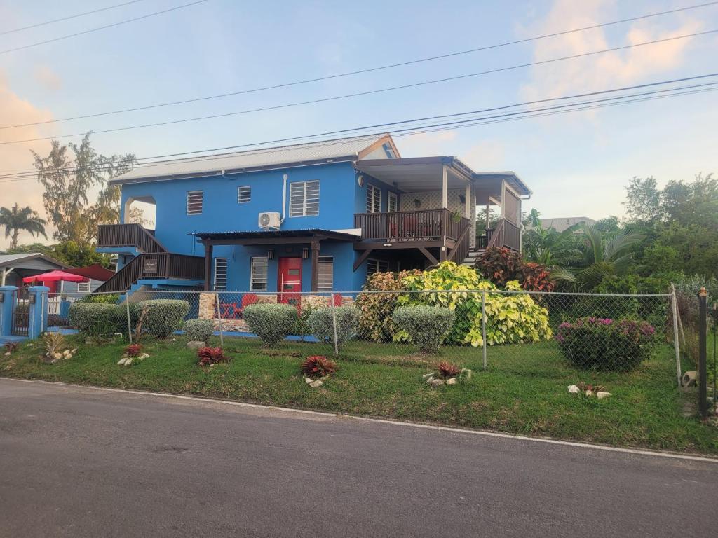 una casa azul al lado de una calle en Silverbuttons Apartments & Eats, en Dickenson Bay