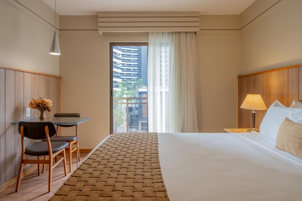 フォルタレザにあるAfago Mareiro Hotelのベッドと机と窓があるホテルの部屋