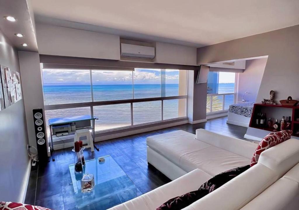 uma sala de estar com um sofá branco e vista para o oceano em Suite Coco CarIbe em Porlamar