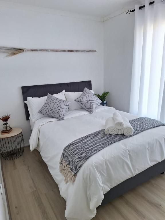 a bedroom with a large bed with white sheets and pillows at Serendip@sea in Cape Town