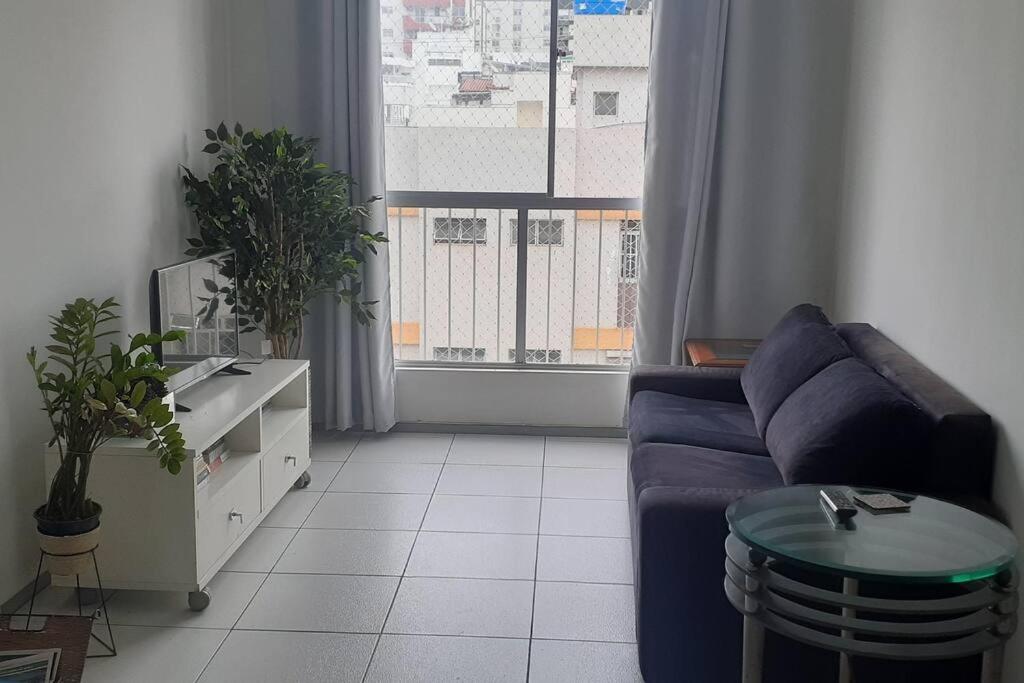 ein Wohnzimmer mit einem blauen Sofa und einem Fenster in der Unterkunft Apart. em Icaraí na quadra praia com garagem Wi-fi in Niterói