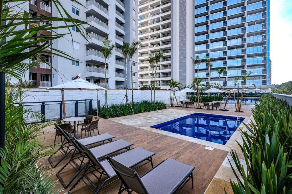 un patio con tavoli e sedie accanto a una piscina di Apartamento Moderno - 8Km Aeroporto GRU a Guarulhos