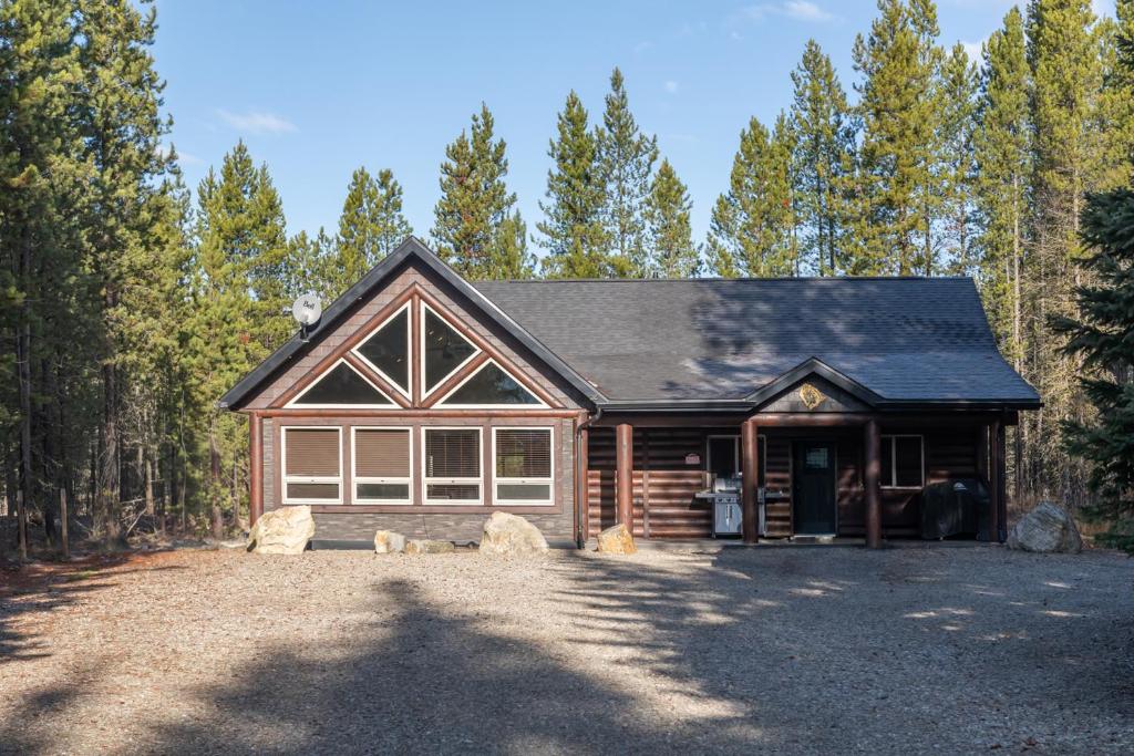 Ein Blockhaus mit einer großen Auffahrt vor Bäumen in der Unterkunft Wolf Den in Valemount