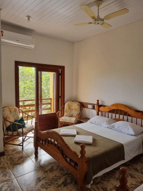 a bedroom with a large bed and two chairs at Pousada dos Quiosques in Viamão
