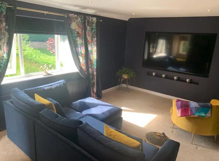 a living room with a blue couch and a tv at The Annexe at Greendyke House in Addingham