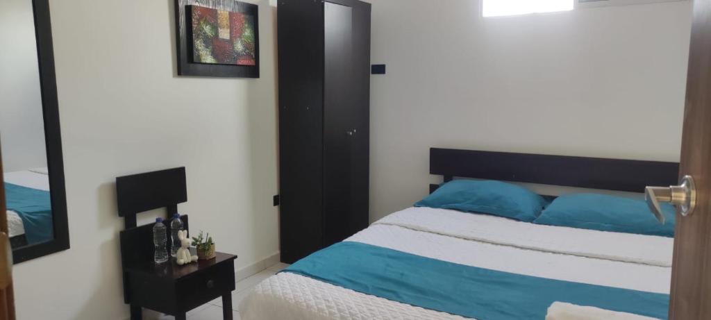 Hotel Mykonos Manta في مانتا: غرفة نوم مع سرير ووسائد زرقاء ومرآة
