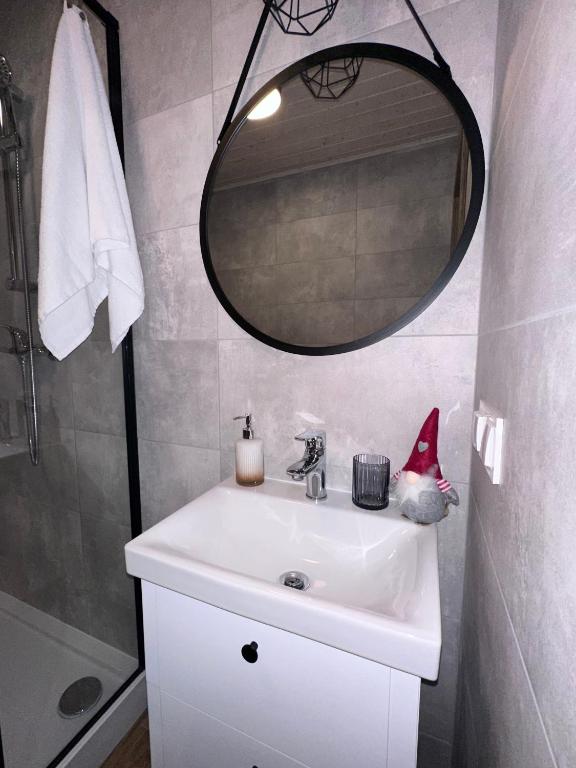 Bathroom sink with round mirror and small gnome decoration.
