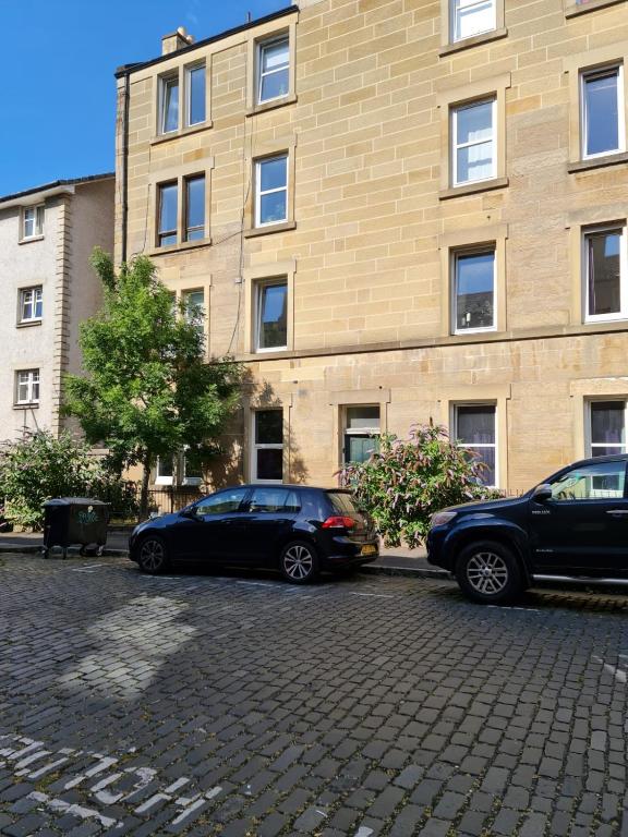 two cars parked in front of a building at Cathcart Place Rooms in Edinburgh