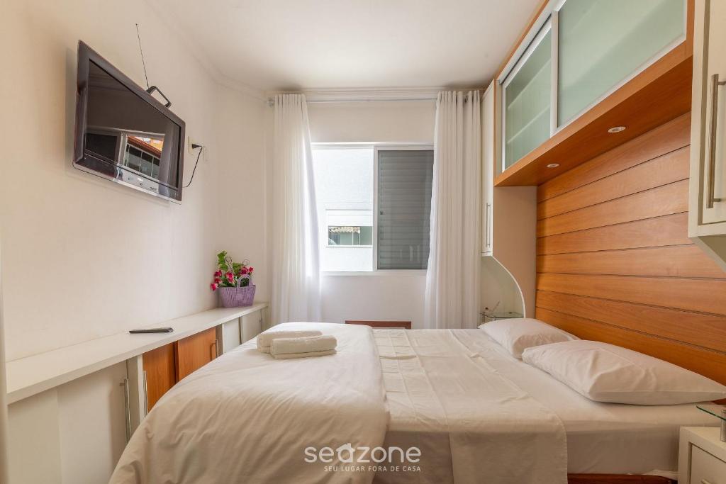 um quarto com uma cama e uma televisão na parede em Apto aconchegante no centrinho dos Ingleses LIB203 em Florianópolis