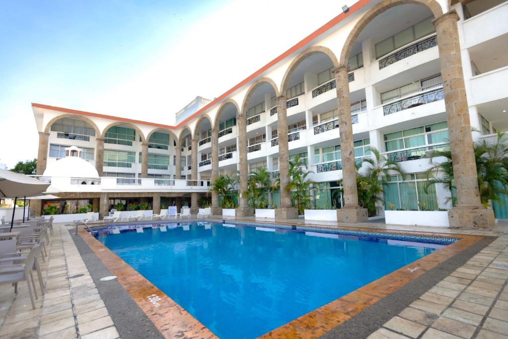 a hotel with a large swimming pool in front of a building at Solamar Inn Mazatlan in Mazatlán