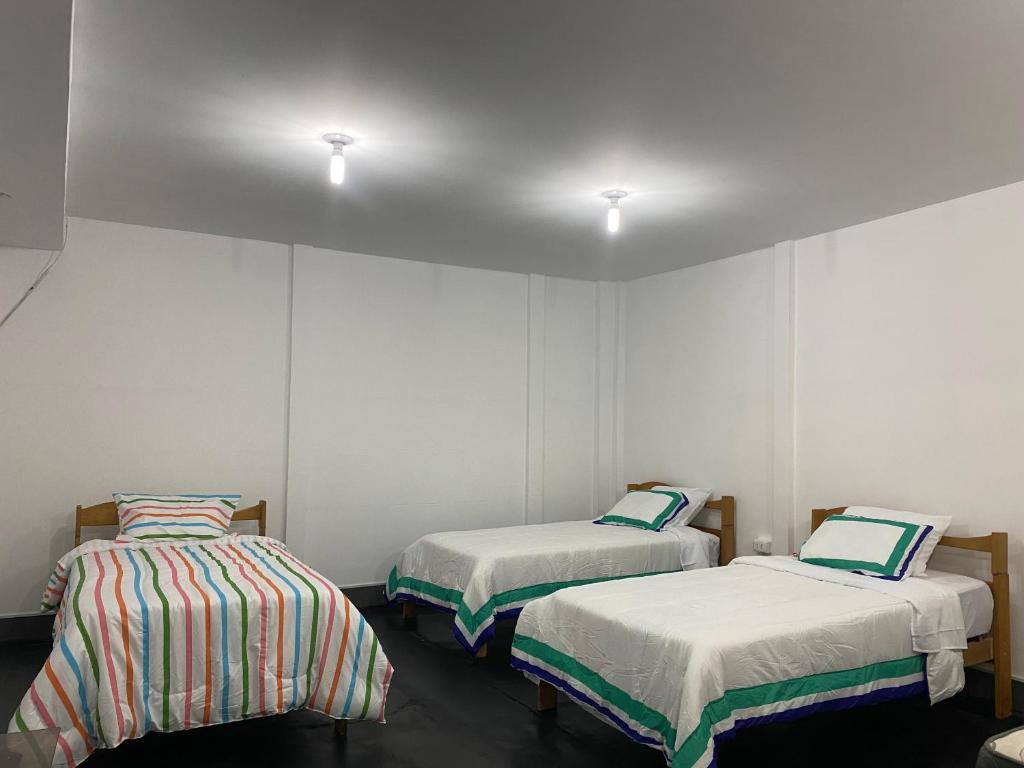 two beds in a room with white walls at Kaypi House in Pisco