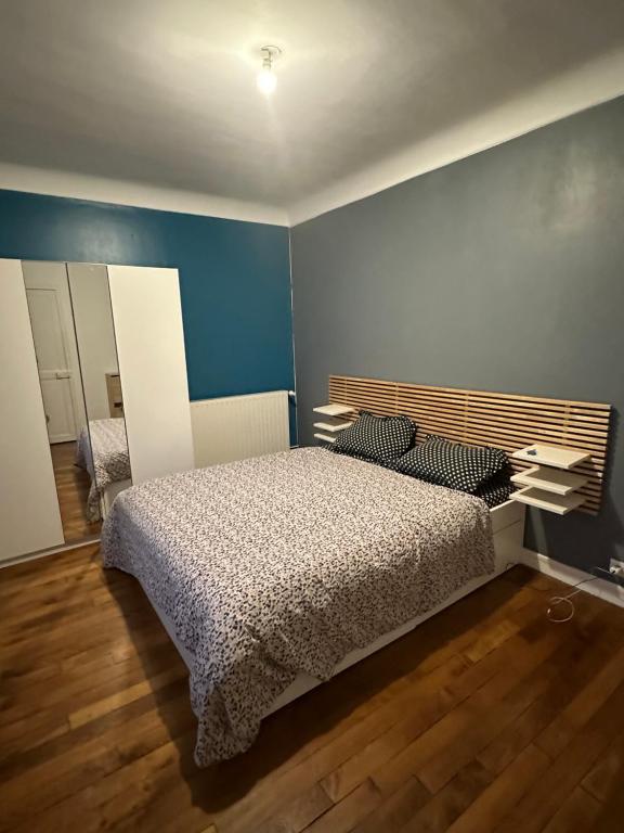 a bedroom with a bed and a blue wall at Appartement meublé à Croissy sur Seine in Croissy-sur-Seine
