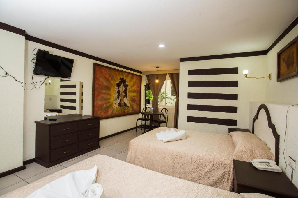 a bedroom with two beds and a desk and a television at Hotel Restaurant 1904 in Apizaco