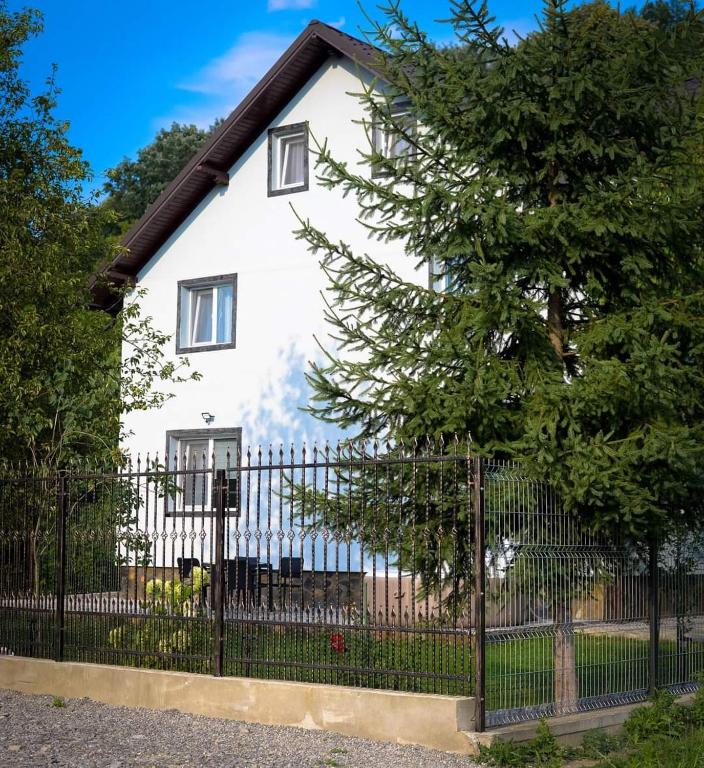 a white house with a fence and a tree at Casa de pe rau in Telega