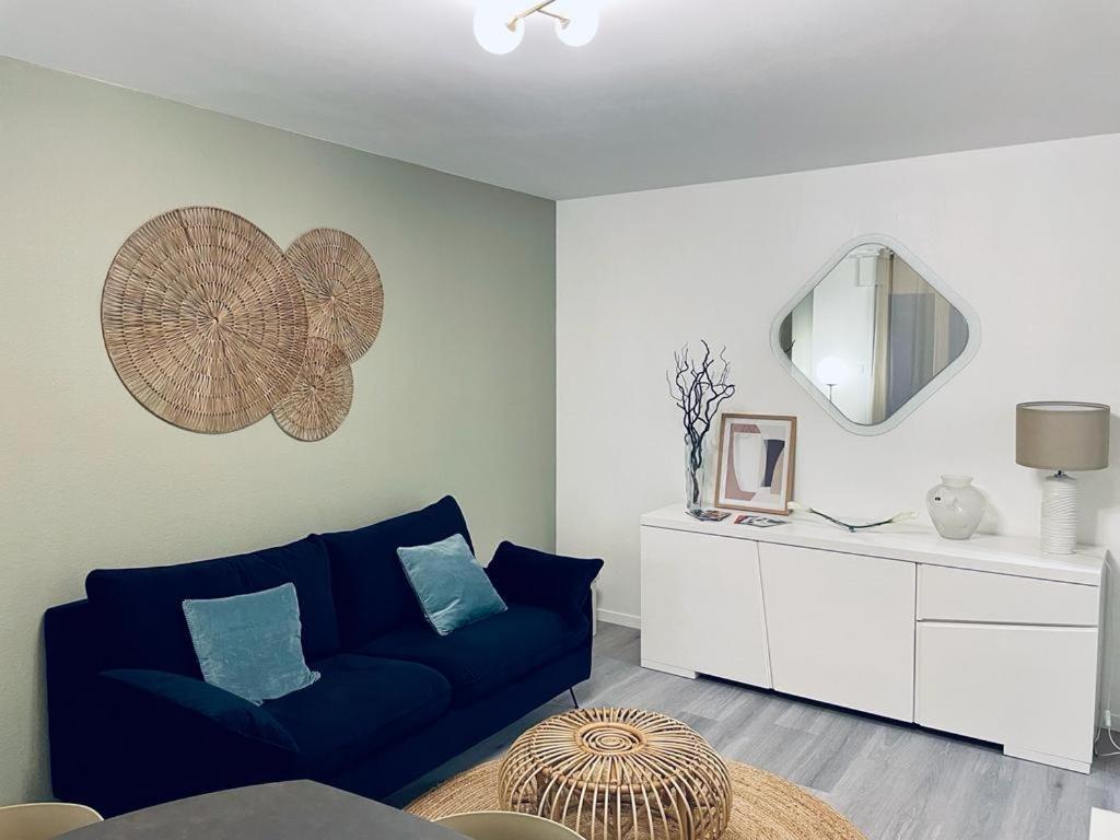 un salon avec un canapé bleu et un miroir dans l'établissement Chez la Clo' - joli 2 pièces, parking gratuit, accès direct tram 2 min à pied, à Strasbourg