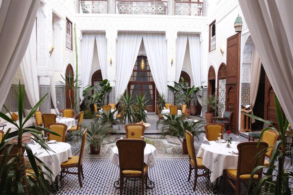 a restaurant with tables and chairs in a building at Riad Alassala Fes in Fès