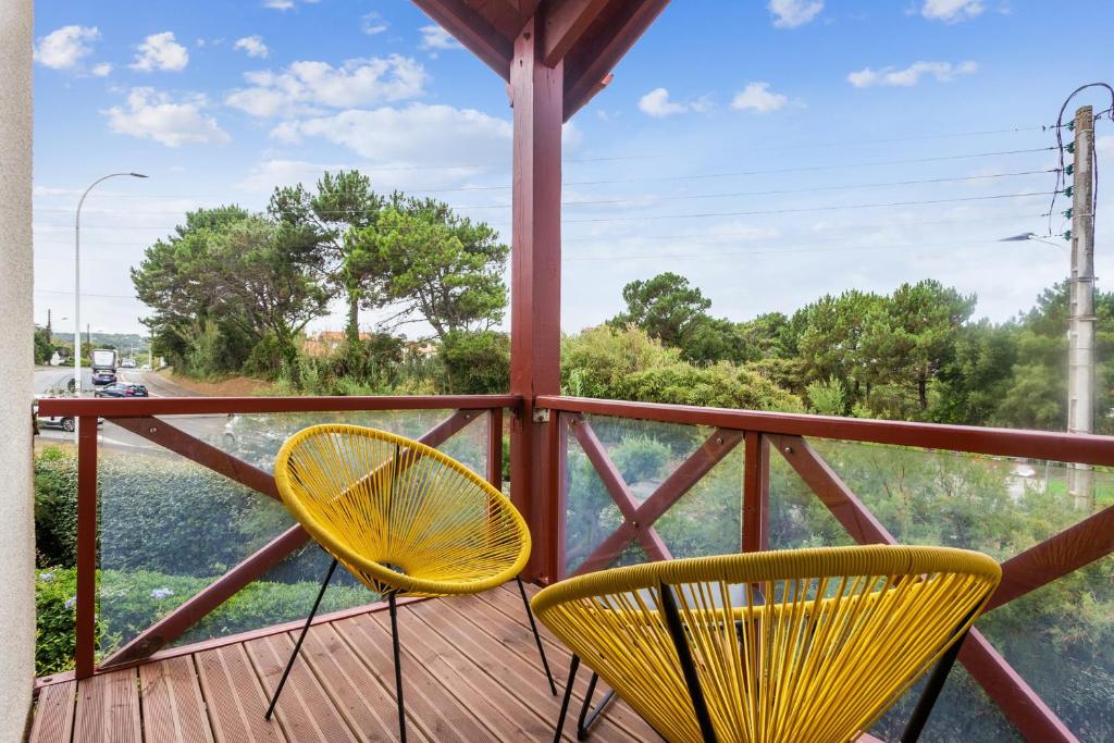 - deux chaises jaunes assises sur une terrasse couverte avec vue dans l'établissement Cosy duplex apartment with ocean view in Biarritz - Welkeys, à Biarritz