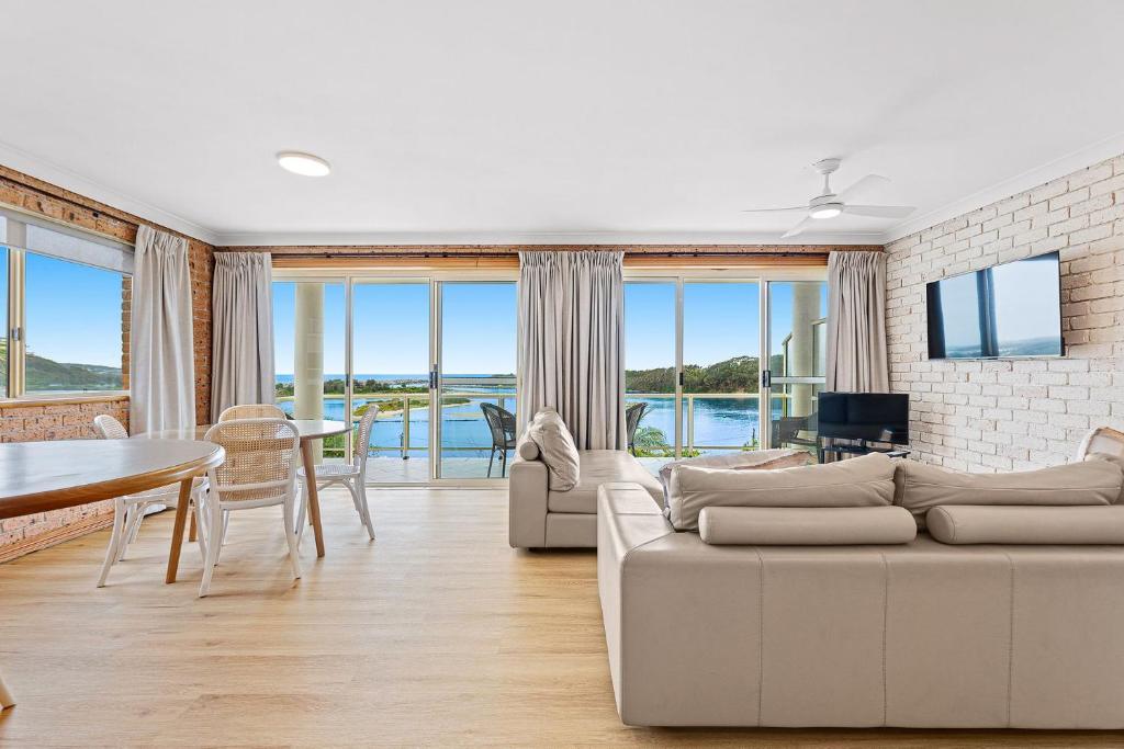 a living room with a white couch and a table and chairs at Grand Pacific 1 Unit 1 - Ground Floor in Narooma