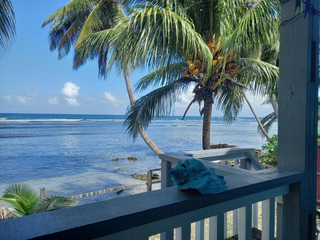 a balcony with a view of the ocean and palm trees at Mx2 Cottage in Calibishie