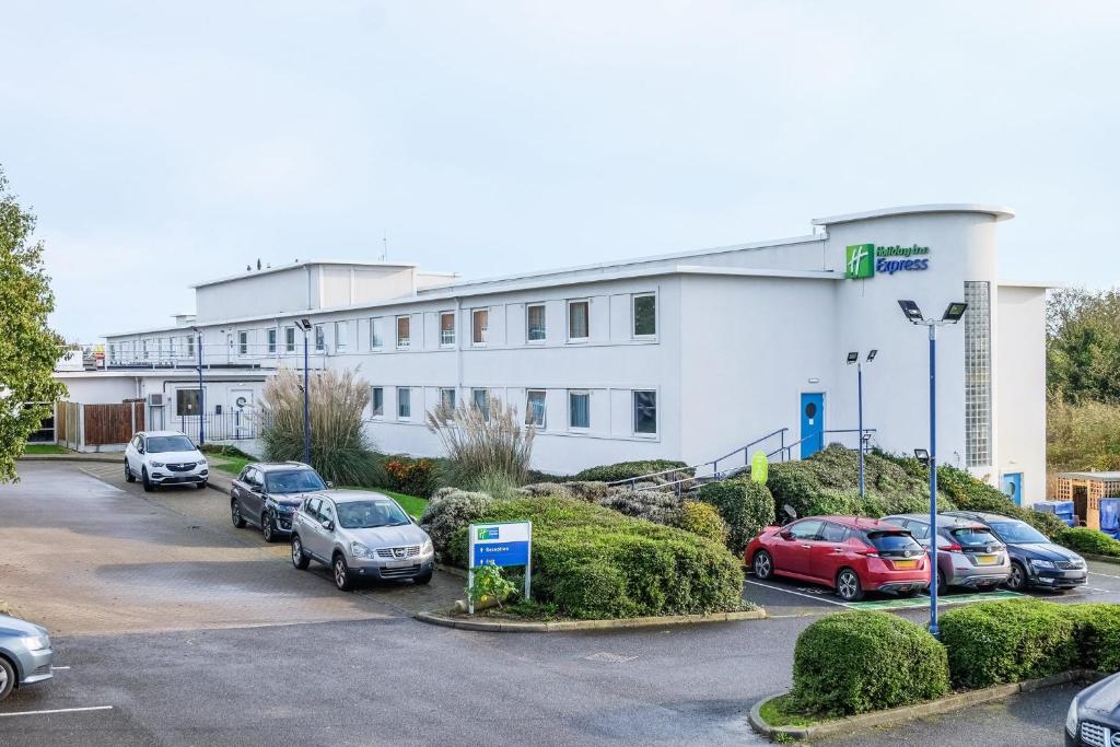 un grand bâtiment blanc avec des voitures garées dans un parking dans l'établissement Holiday Inn Express Ramsgate – Minster, an IHG Hotel, à Minster