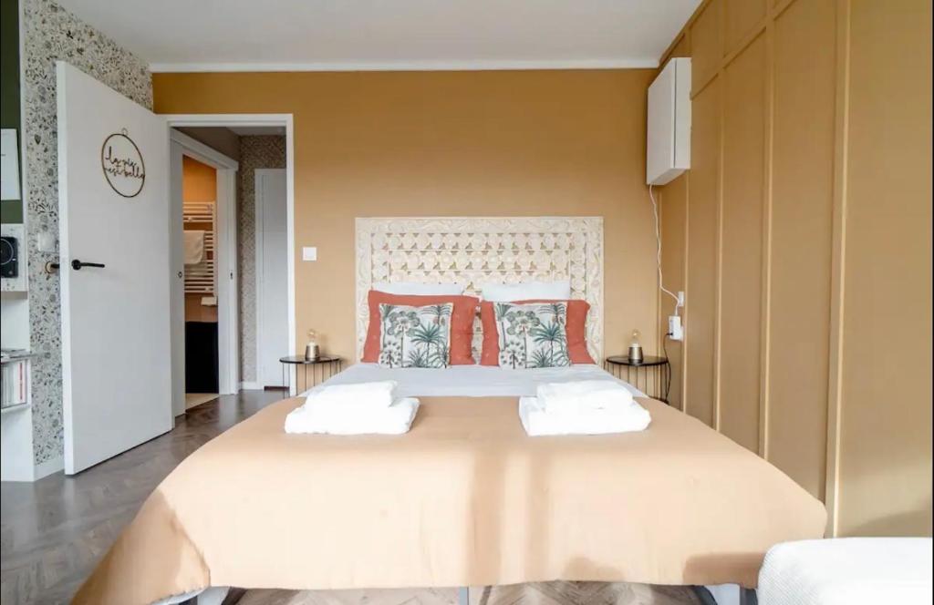 een slaapkamer met een groot bed met kussens bij Studio La Petite Oasis - 10min à pieds plage et centre ville in Courseulles-sur-Mer