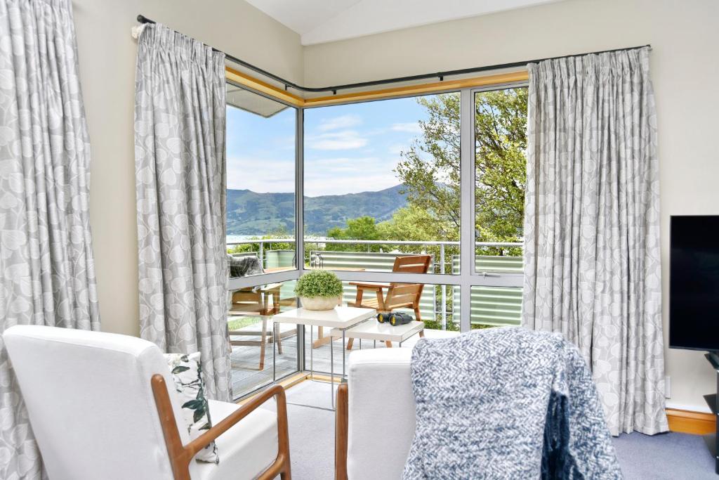 a living room with a table and chairs and a large window at Watson Street - Bookahome in Akaroa