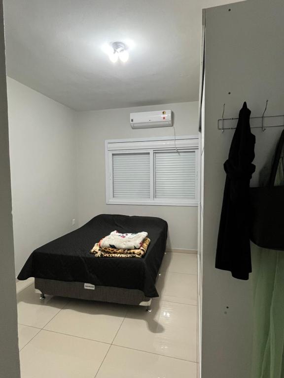 a small bedroom with a bed and a window at Casa com piscina em Imbé/Rs in Imbé