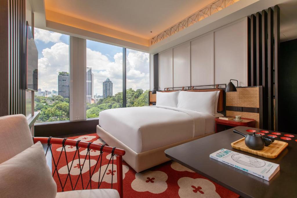 A bright bedroom with a large bed facing a broad city-and-park outlook.