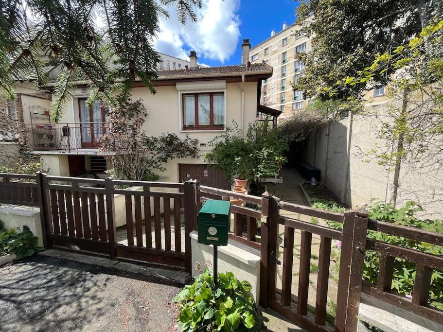 a house behind a wooden fence with a green box at P1- Maison 2min metro PARIS-EXPO 3 chambres 3 lits in Châtillon