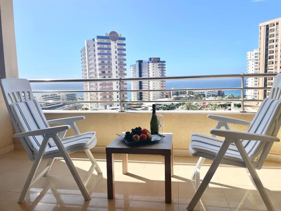 two chairs and a table with a bottle of wine on a balcony at Magnífico Sol Paraíso in Adeje