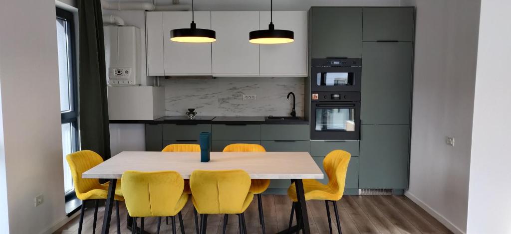 a kitchen with a table and yellow chairs at Modern Apartment with great terasse and mountain view in Braşov