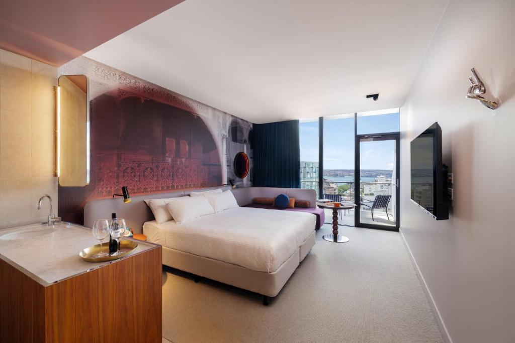 a bedroom with a bed and a couch and a tv at Hotel Indigo Sydney Potts Point, an IHG Hotel in Sydney