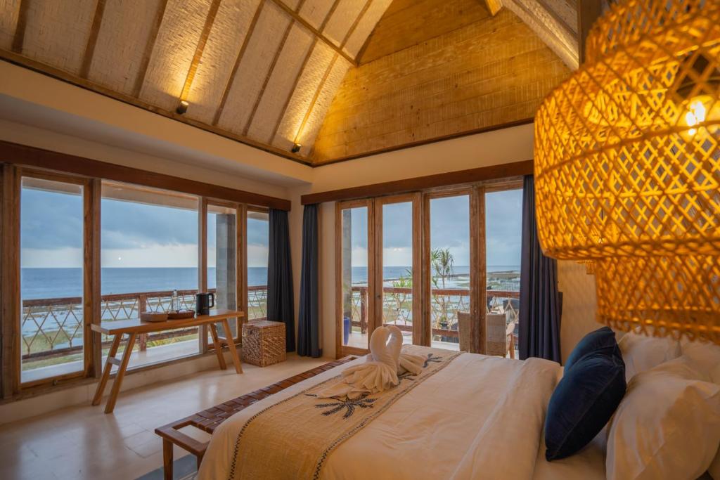 a bedroom with a bed with a view of the ocean at ALANA PENIDA HOTEL in Batununggul