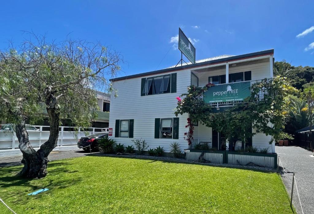 a white building with a sign on top of it at Peppertree Lodge & Backpackers in Paihia