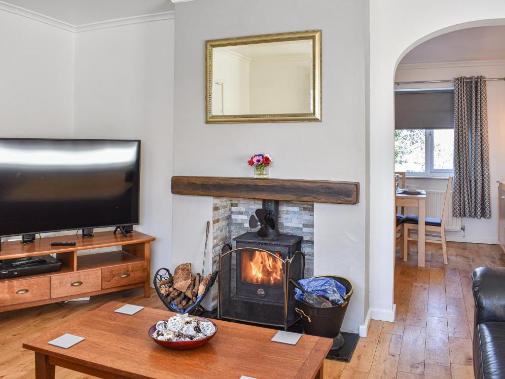a living room with a fireplace and a television at Glebeside Retreat in Satley