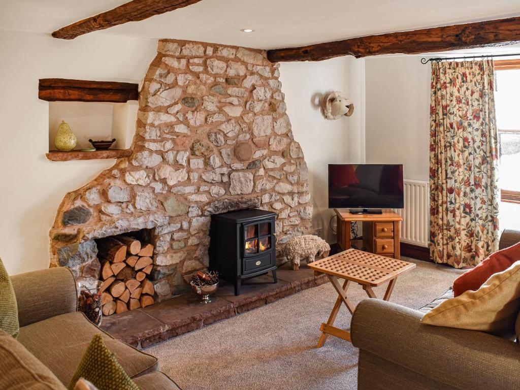 a living room with a stone fireplace and a tv at Quince Cottage in Clifton