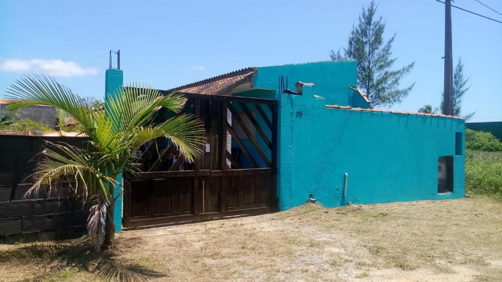 ein blaues Haus mit einem Tor und einer Palme in der Unterkunft Apartamentos Ilha Comprida in Ilha Comprida
