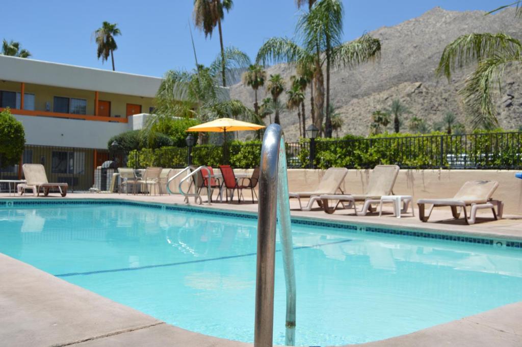a swimming pool with chairs and an umbrella at Musicland Hotel in Palm Springs