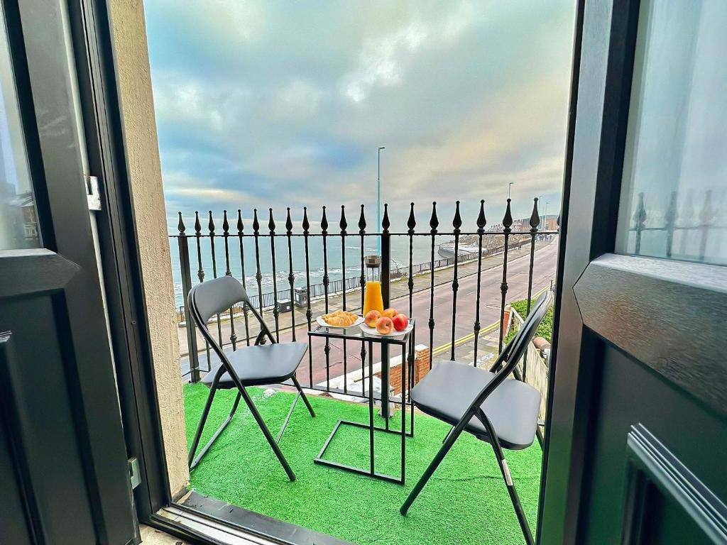 a balcony with two chairs and a table with a view of the ocean at Victoria House By The Sea in Whitley Bay