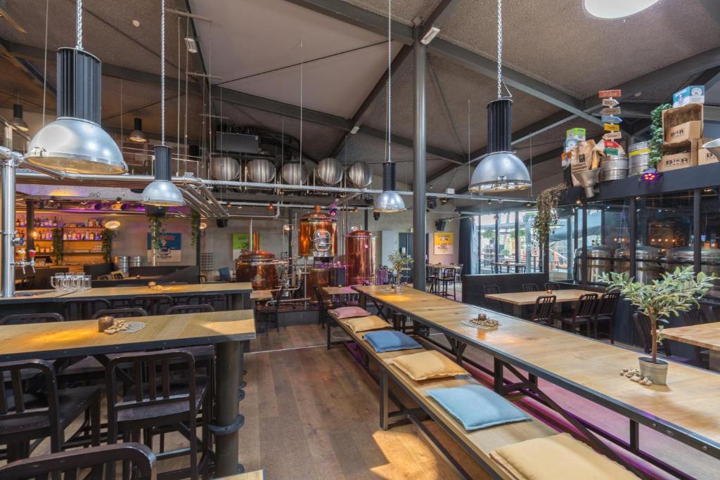 a restaurant with wooden tables and chairs and a bar at Leonardo Hotel Almere City Center in Almere