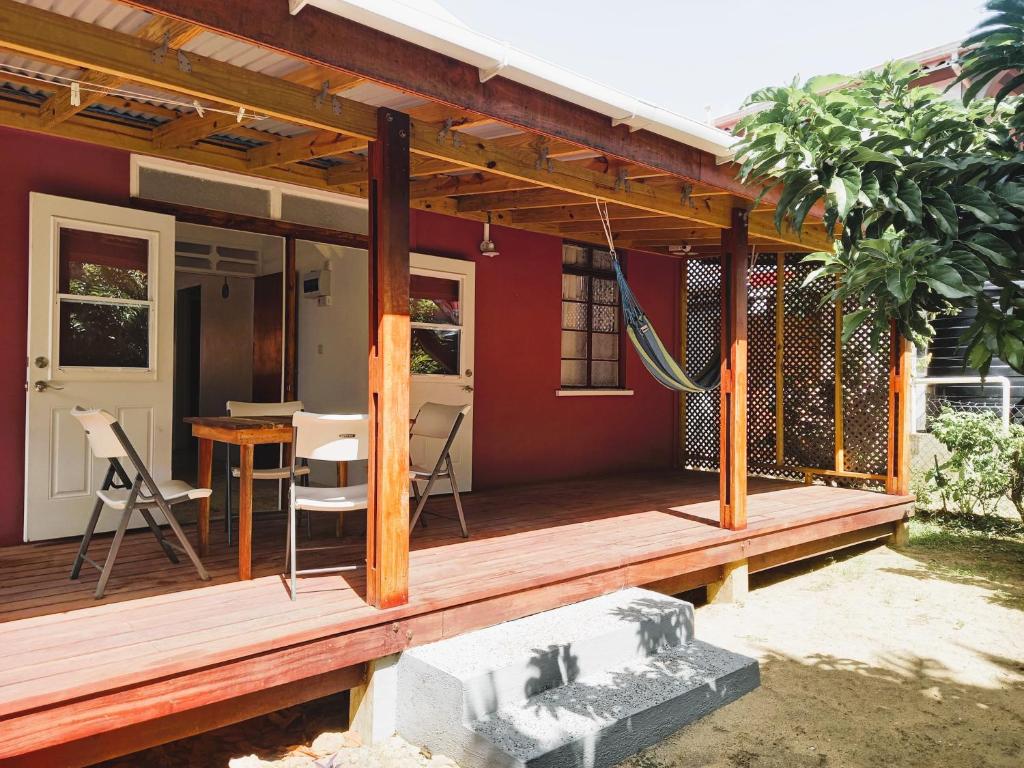 Casa con terraza de madera con mesa en Dado's Place, en Calibishie