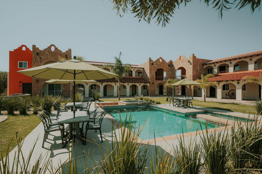 un complejo con piscina, mesas y sillas en Hacienda Los Olivos, Valle de Guadalupe en Rancho Grande
