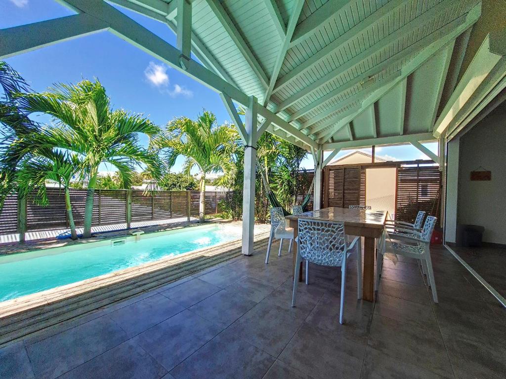 a patio with a table and chairs and a pool at cannelle in Sainte-Anne