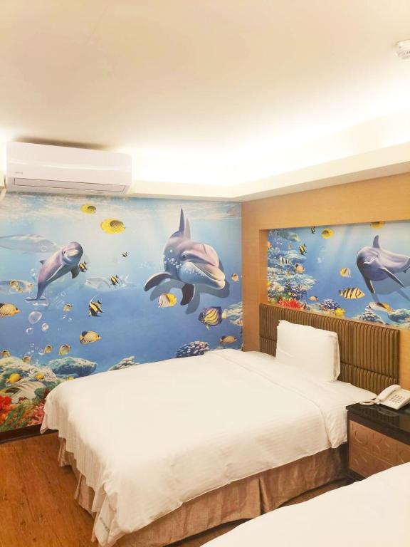 a bedroom with two beds and a painting of dolphins at JinShan Sakura Bay Hot Spring Hotel in Jinshan