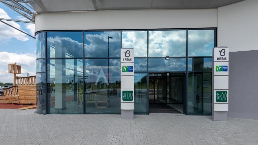 a large glass building with a sign in front of it at Holiday Inn Express - Hamburg South A7-AS42, an IHG Hotel in Egestorf